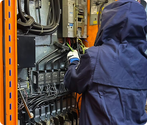 Electrical safety engineer working on a switchboard in arc-flash PPE
